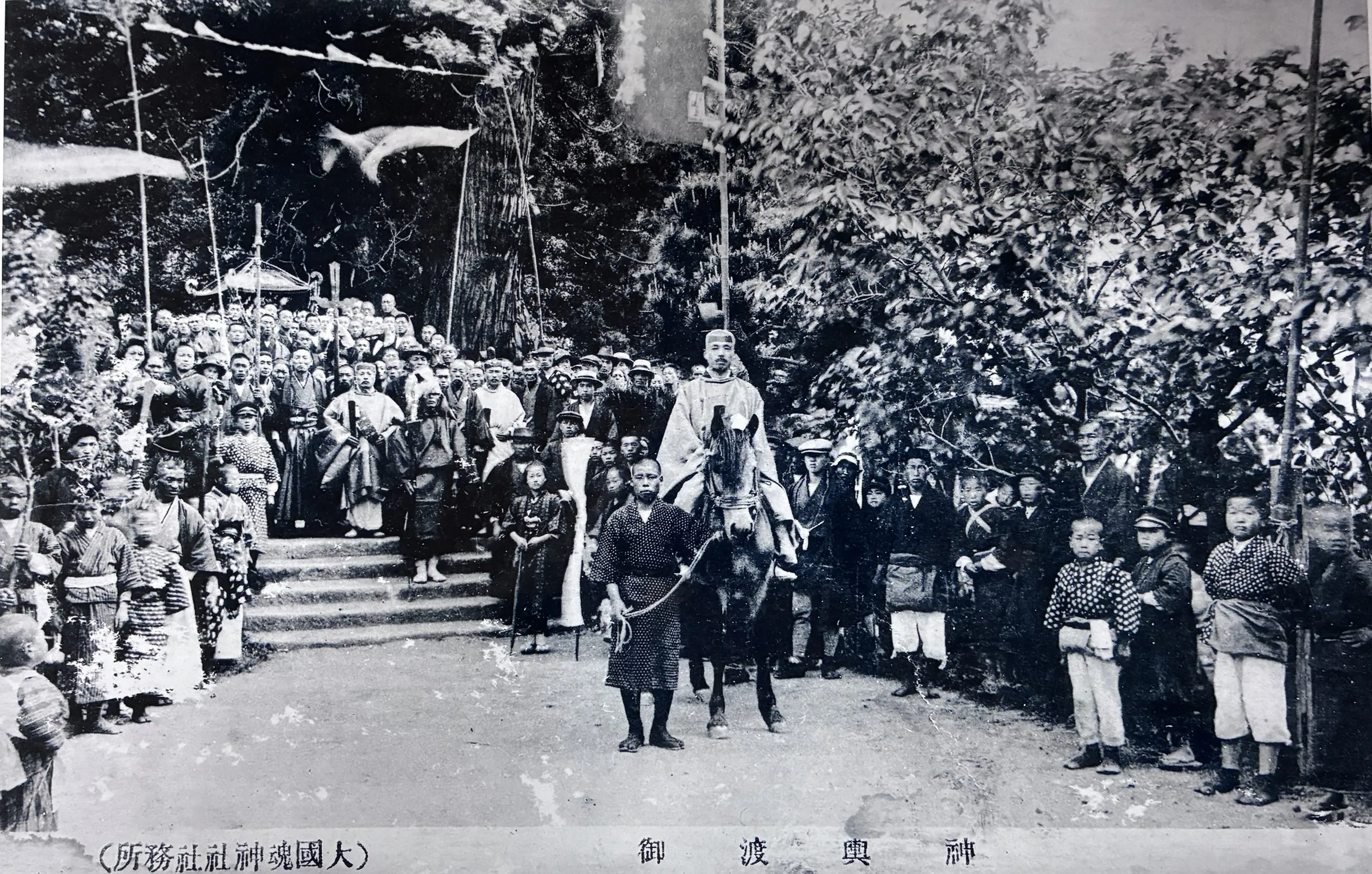 石段の前に集まる人々と、馬に乗った神職。「神輿渡御」と刷られた絵はがき